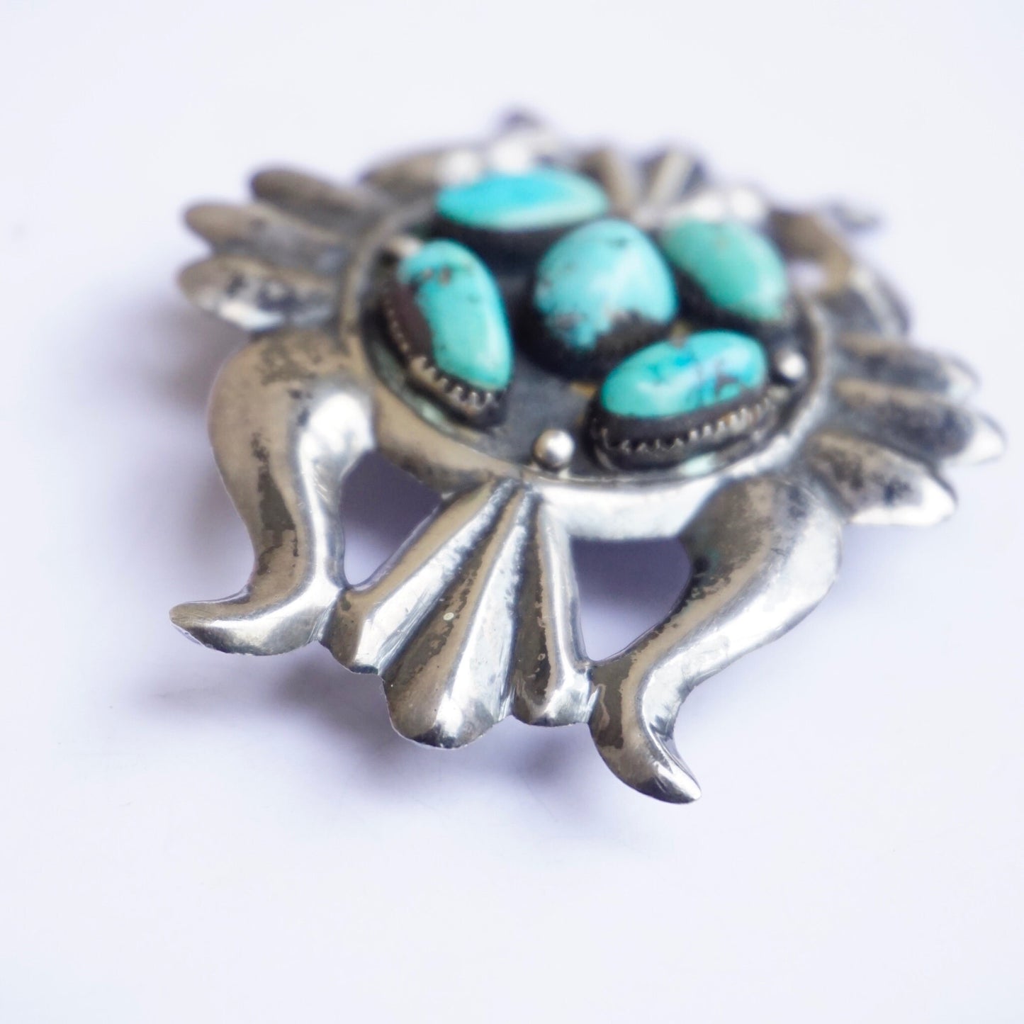 Vintage Navajo sterling silver belt buckle with multiple turquoise stones arranged in a floral design, crafted in the traditional Native American style of old pawn silver jewelry.