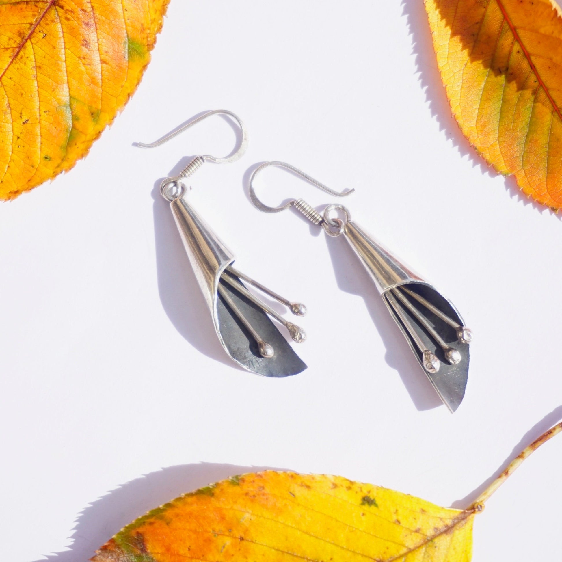 Vintage sterling silver modernist dangle earrings with jingle jangle chimes on autumn leaves background