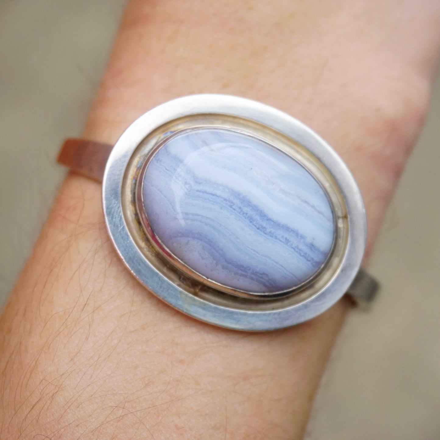 Vintage blue lace agate sterling silver bracelet on a person's wrist, featuring a raised oval blue stone set in a 925 silver setting, made by Leenhardt Geneve.