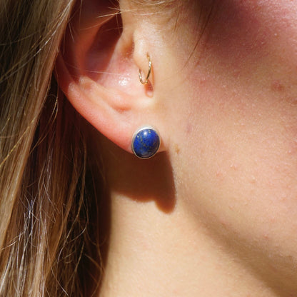 Close-up of an ear with a vintage sterling silver stud earring featuring a round blue lapis lazuli gemstone.