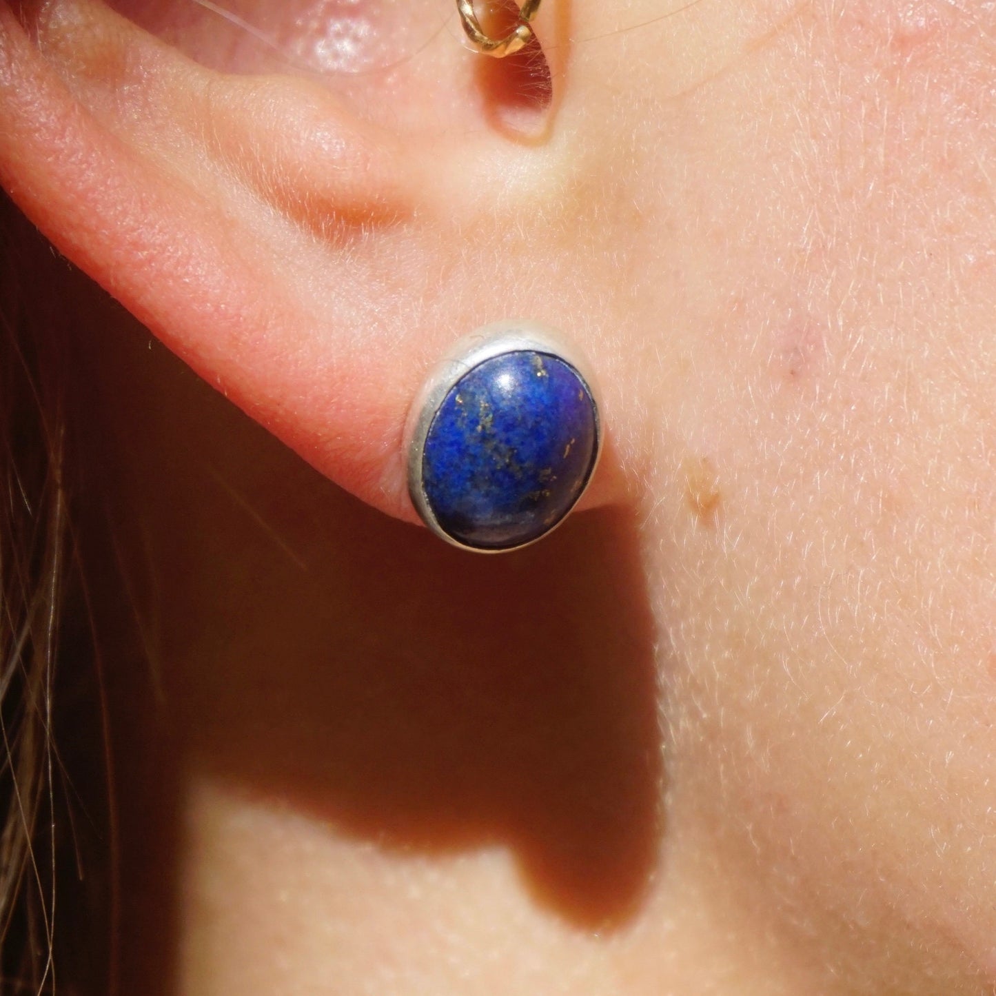 Vintage lapis lazuli sterling silver stud earring worn on an ear, showcasing the deep blue stone against skin.