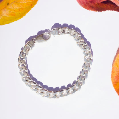 Vintage sterling silver Cuban link bracelet on white background with autumn leaves