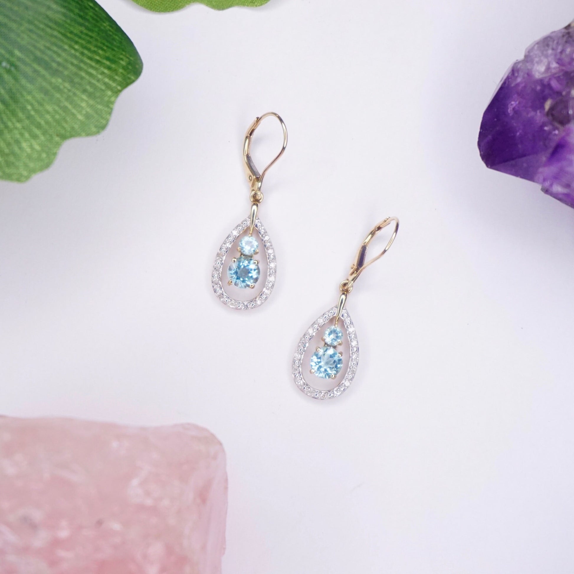 14K gold teardrop earrings with aquamarine and diamond accents on white background with pink and purple stones