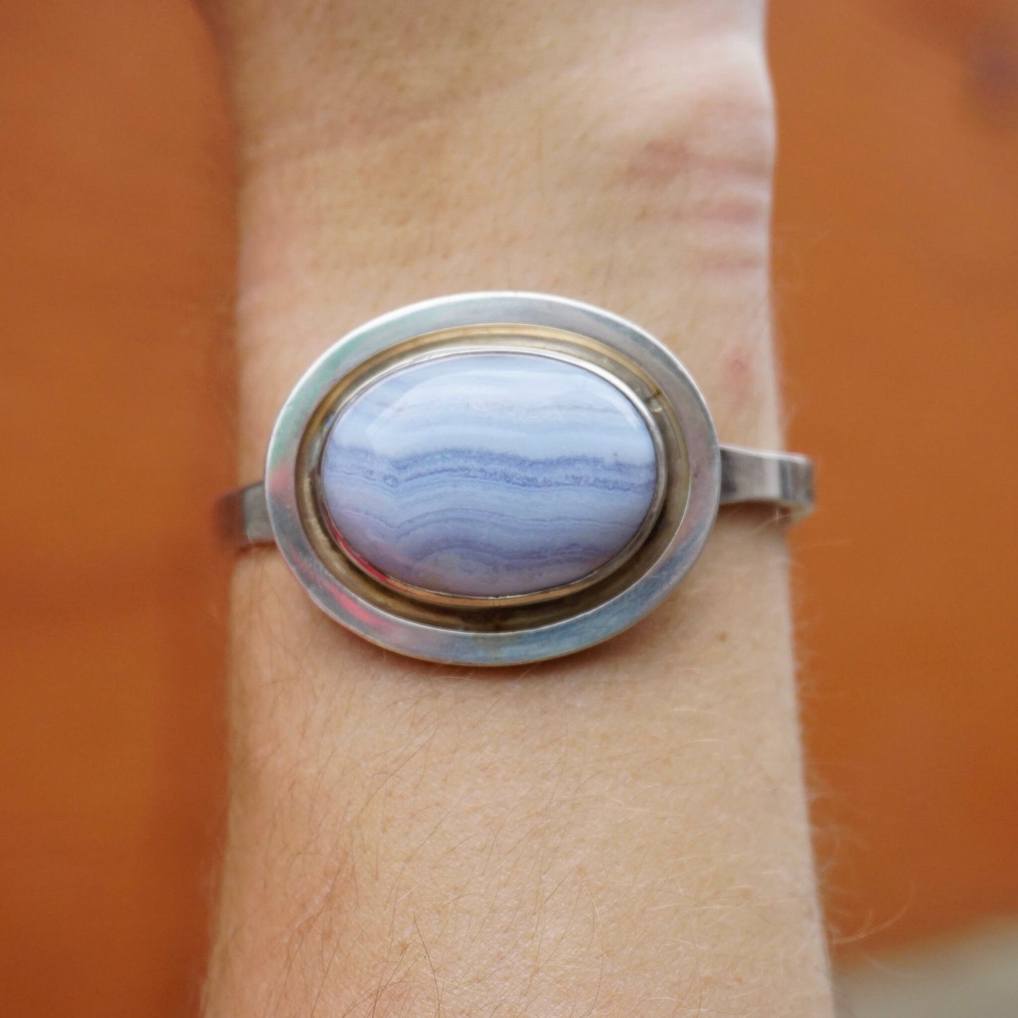 Vintage blue lace agate sterling silver bracelet on wrist, featuring raised oval blue stone in silver setting.