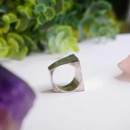 Vintage sterling silver signet ring with thick rectangular face on white surface with succulent plants in background