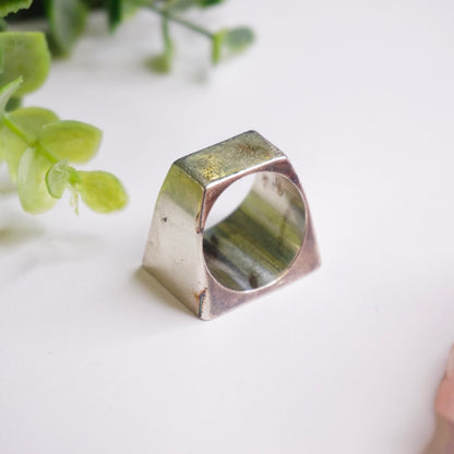 Vintage sterling silver signet ring with thick rectangular face and solid construction, suitable as a men's silver ring or unisex 925 jewelry piece, shown with green foliage in the background.