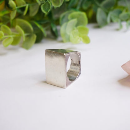 Vintage sterling silver signet ring with thick rectangular design, solid silver ring with large face, men's 925 silver jewelry displayed with greenery in background