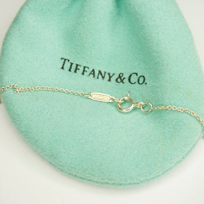 Vintage Tiffany & Co. sterling silver lariat necklace with T&CO letters on delicate chain, displayed on soft green fabric.