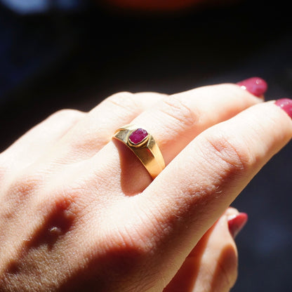 Vintage 10K gold band ring with a small, red ruby gemstone on a hand, showcasing the ring's design and ruby setting against the skin.