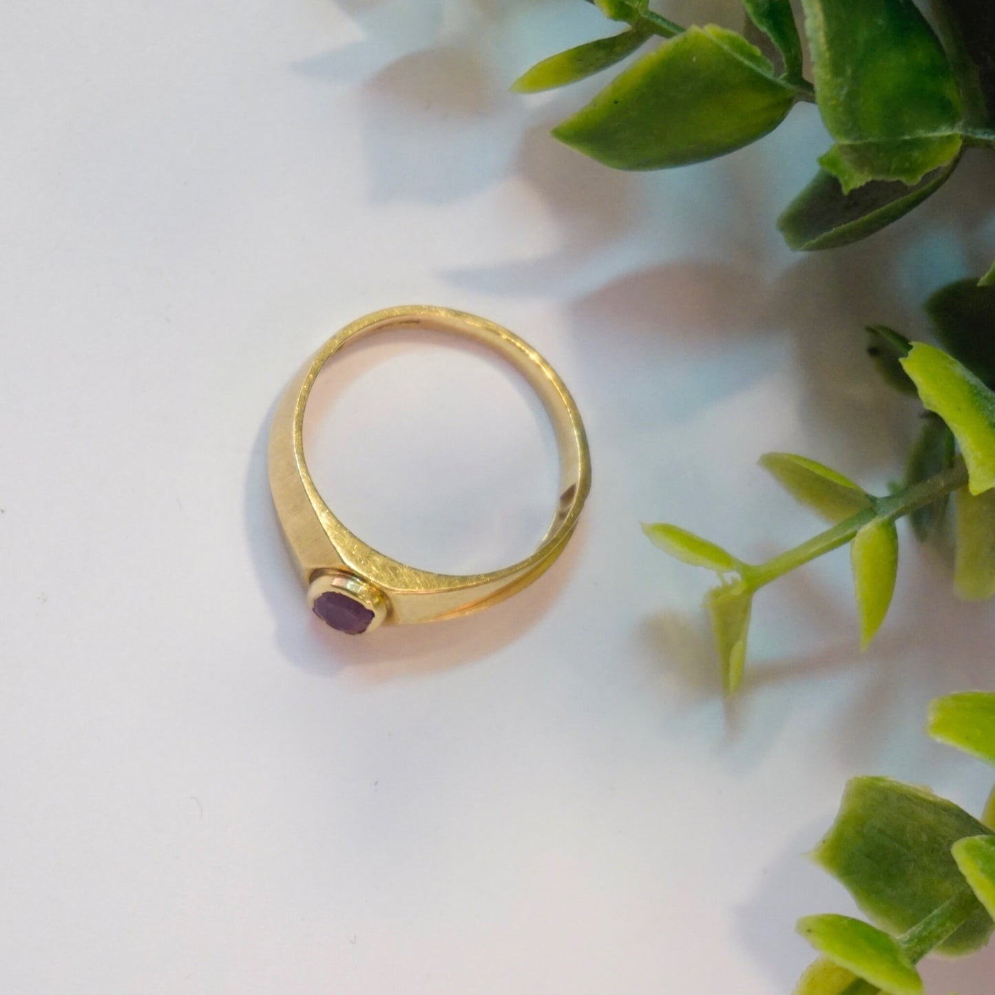 10K gold vintage ring with authentic ruby gemstone on marble background with greenery