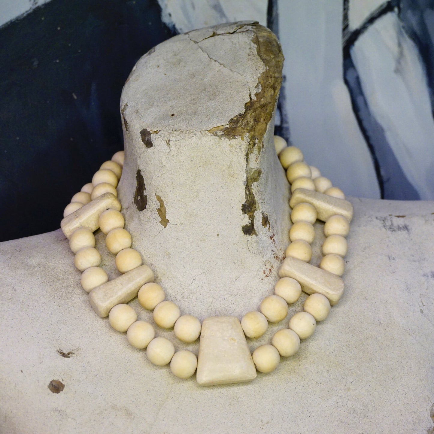 Vintage Gerda Lynggaard Monies chunky wooden necklace featuring a two-strand design with creamy white wooden beads and a large, textured off-white stone pendant, set against a mottled gray background.