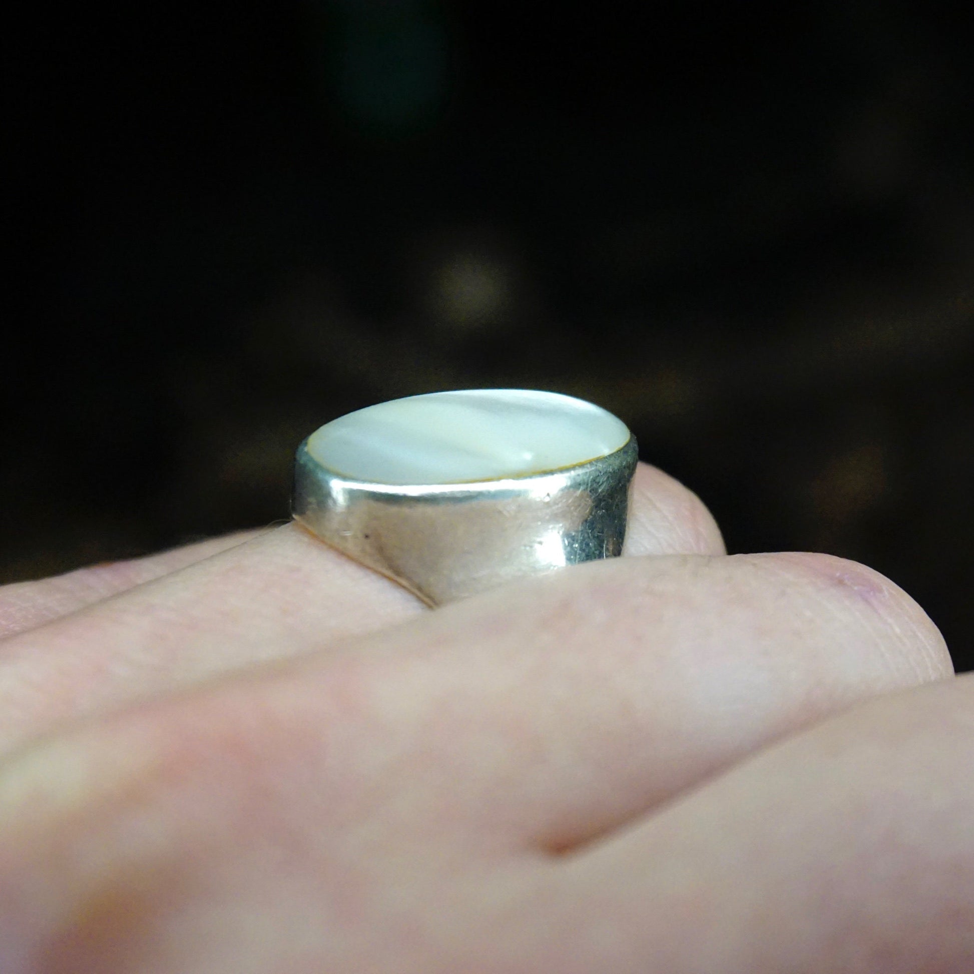 Vintage sterling silver ring with iridescent mother of pearl inlay held in hand, closeup view