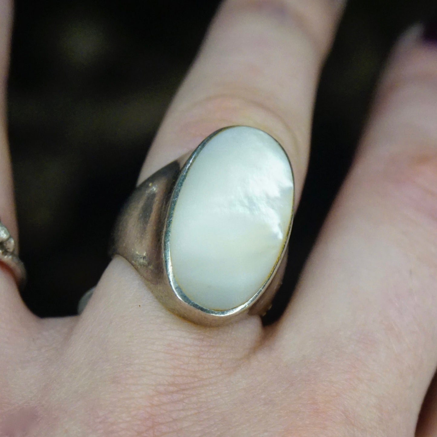 Vintage sterling silver ring with iridescent mother of pearl stone on a person's finger