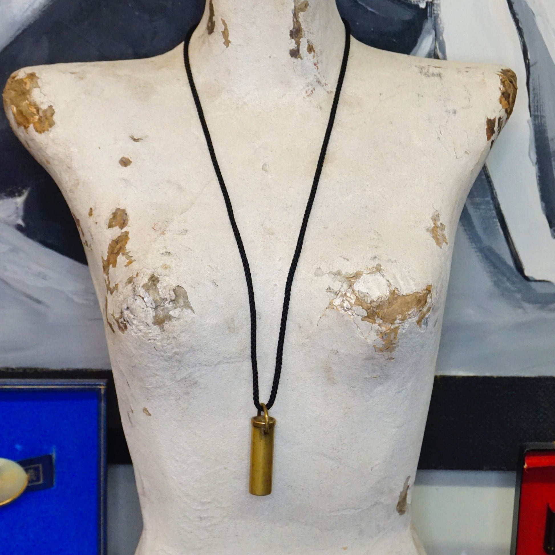 Vintage brass kaleidoscope pendant necklace on mannequin, made in France, with black rope chain. Unique kaleidoscope jewelry showing wear and patina on the brass surface.