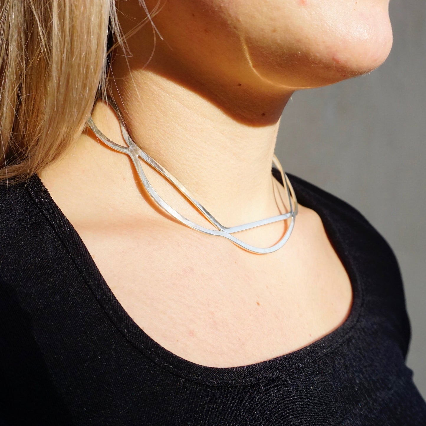 Vintage sterling silver cut out collar necklace from Mexico, 925 silver choker necklace with wavy, modern minimalist design, worn on a woman's neck against a black top.