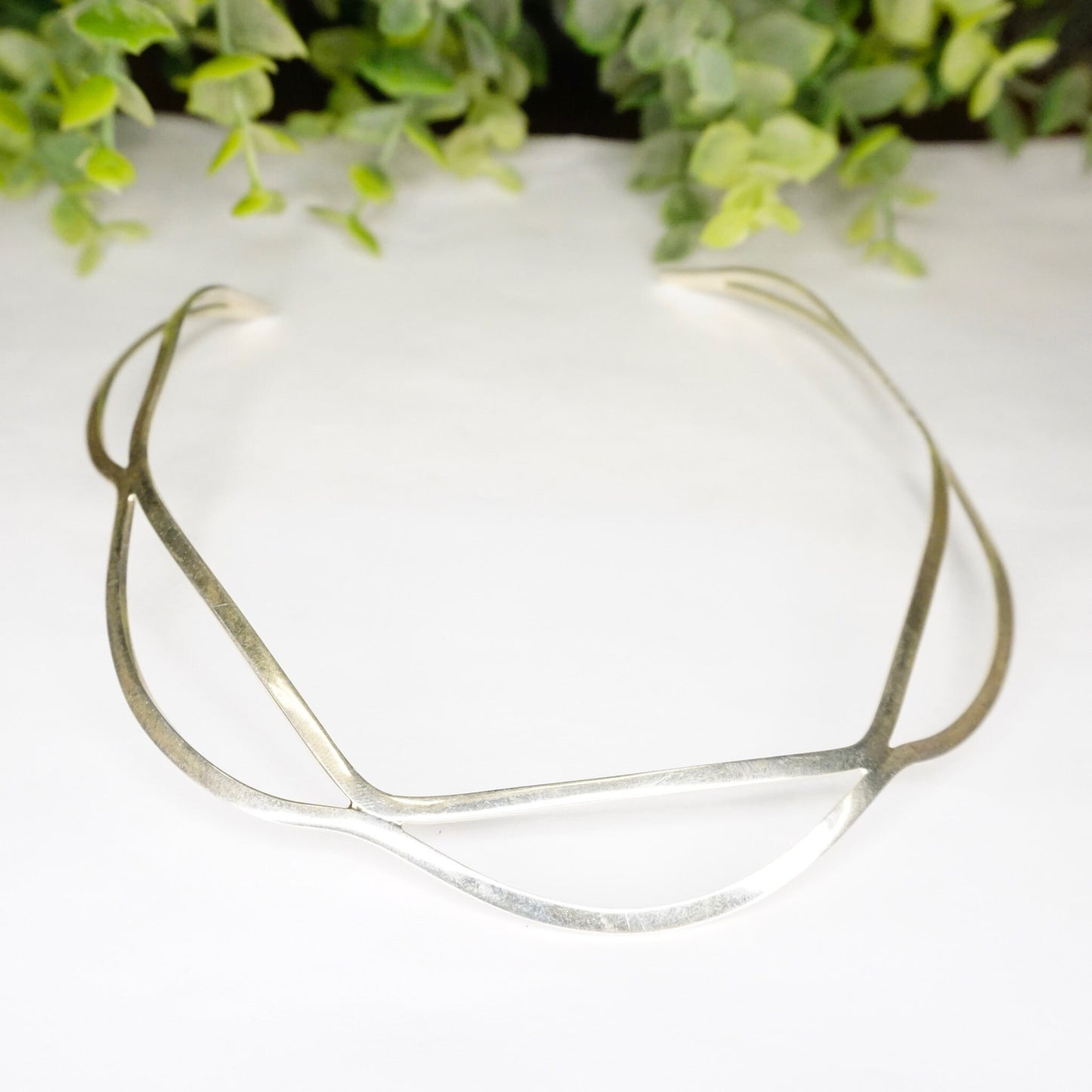 Vintage sterling silver wavy cut-out collar necklace from Mexico, 925 silver modern minimalist choker jewelry, displayed with green foliage background.