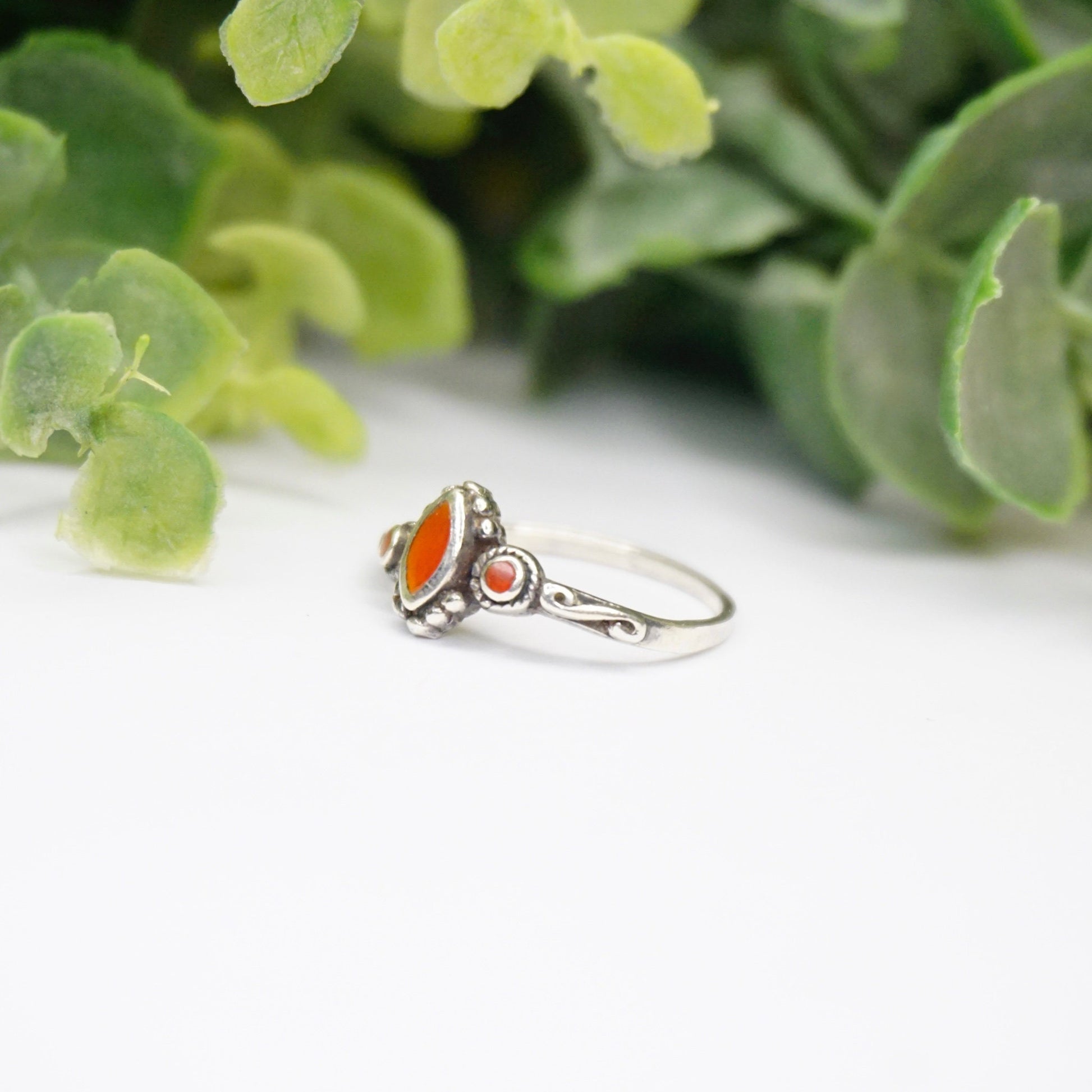 Vintage sterling silver ring with red stone or glass accent, featuring delicate swirl details on a thin band, 925 silver.