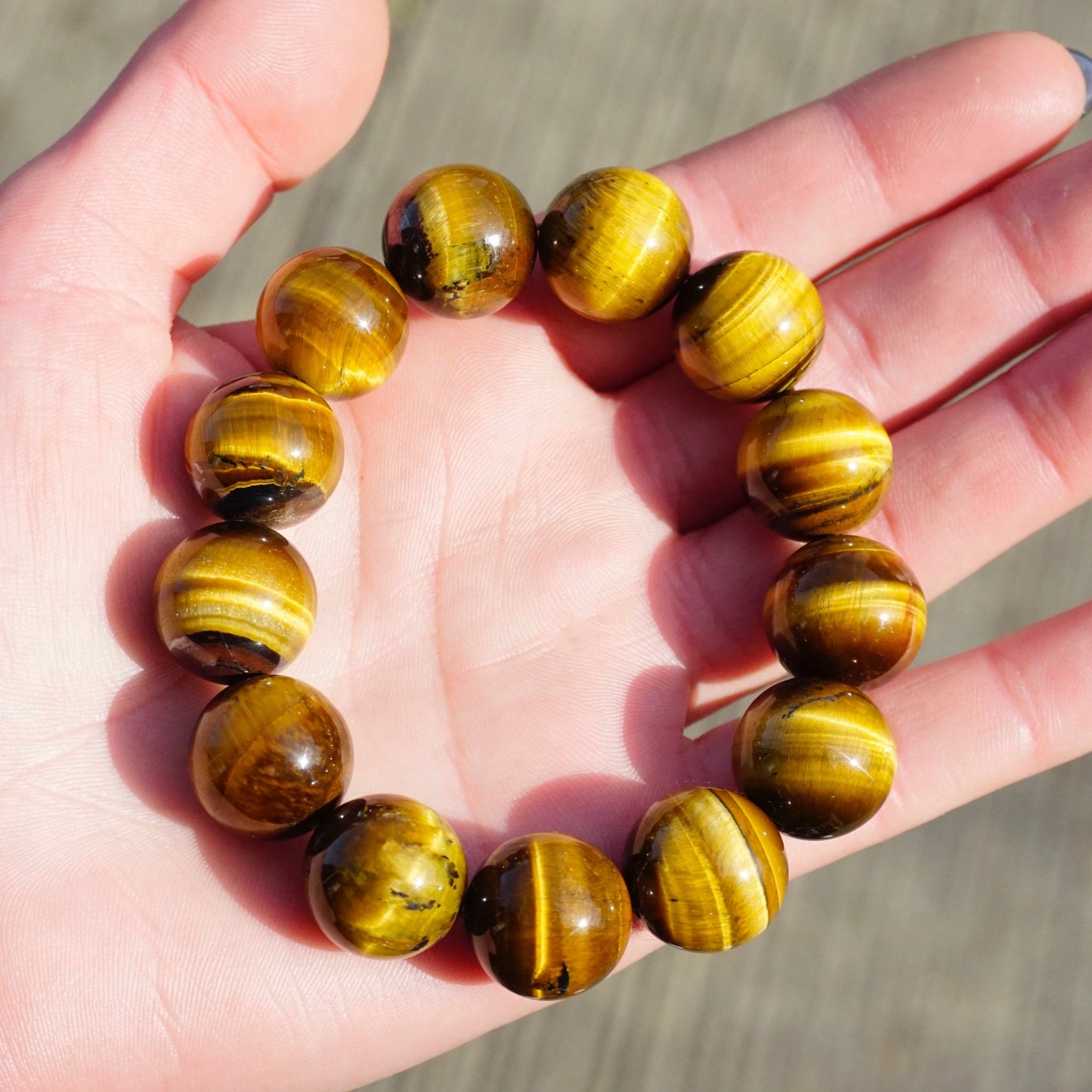 Vintage tigers eye beaded stretch bracelet held in palm, showing large round golden brown striped gemstone beads.