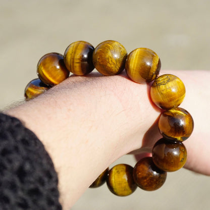 Vintage tiger's eye beaded stretch bracelet with beautiful golden brown large round beads held in a hand.