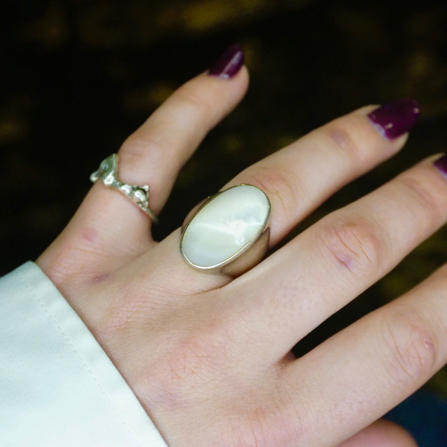 Vintage sterling silver mother of pearl ring on a person's hand, showing the iridescent oval-shaped mother of pearl stone set in a simple polished silver band. The ring has an elegant, unisex design.