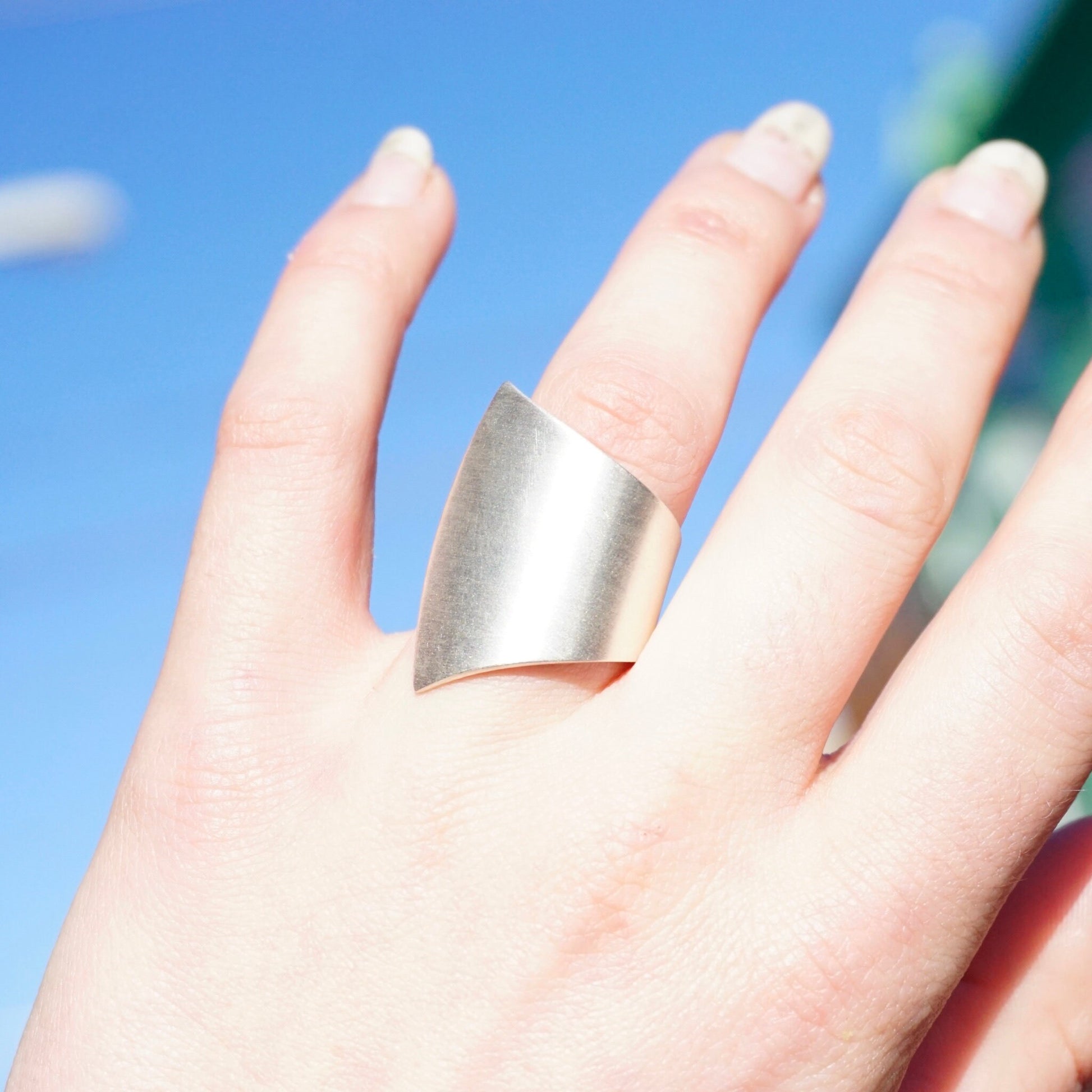 Vintage sterling silver wrap ring on a hand against a blue sky background, featuring a modernist fan design. Rare designer 925 silver jewelry piece by Kathy Lynn Mayeda, stamped KLM.