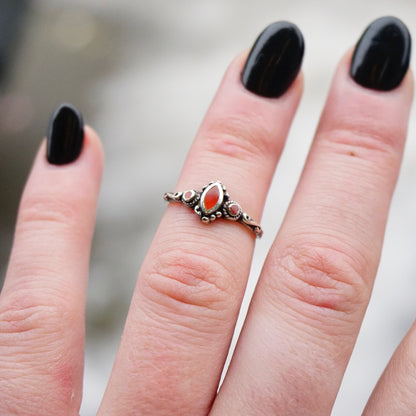 Vintage sterling silver ring with red stone or glass accent on a hand, showcasing petite silver band with swirl details and thin 925 sterling silver design.