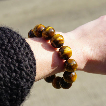 Vintage tigers eye beaded stretch bracelet on a wrist, showcasing large, round, golden brown tigers eye beads against a neutral background.