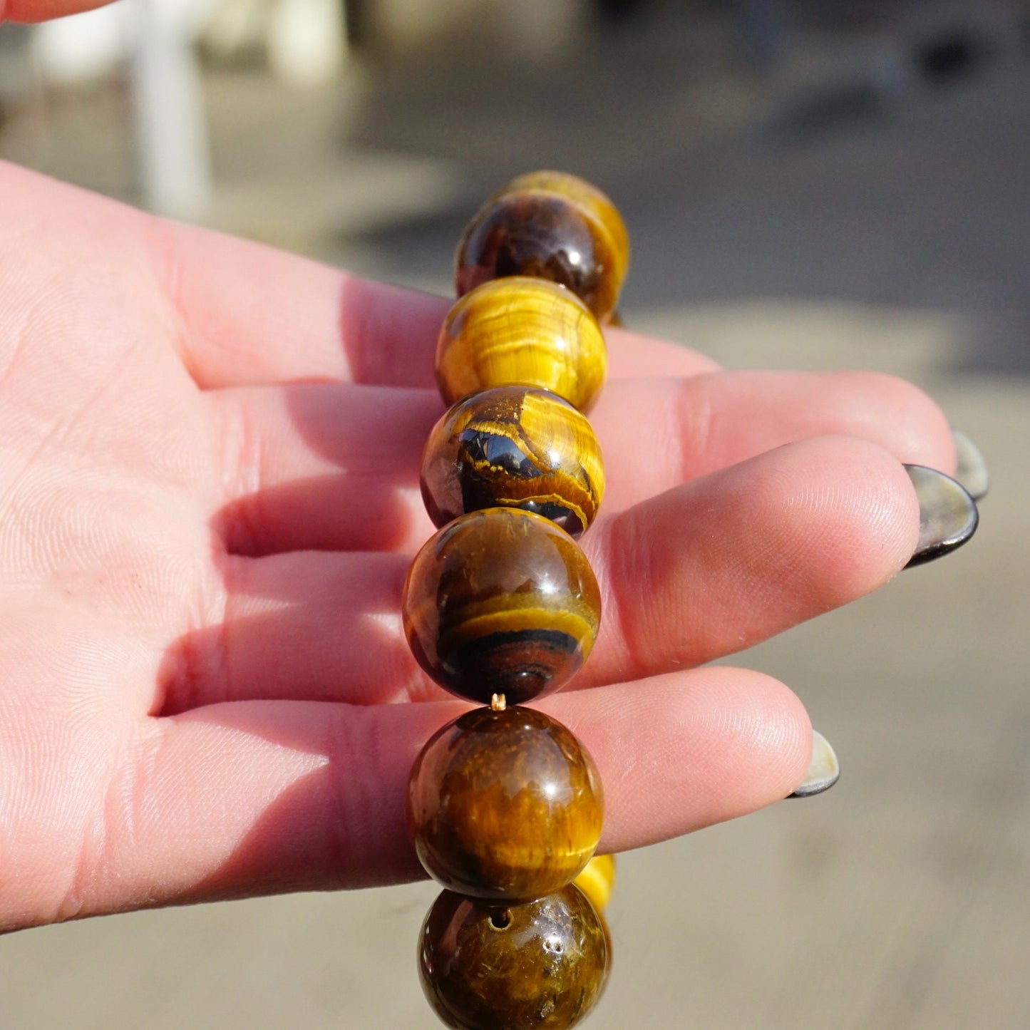 Vintage tigers eye beaded stretch bracelet held in palm, showcasing large, round, golden brown tigers eye gemstone beads.