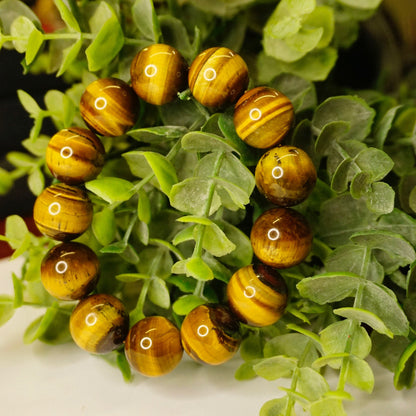 Vintage tiger's eye bead bracelet featuring large, round, golden-brown beads nestled in lush green foliage, creating a beautiful and natural accessory.