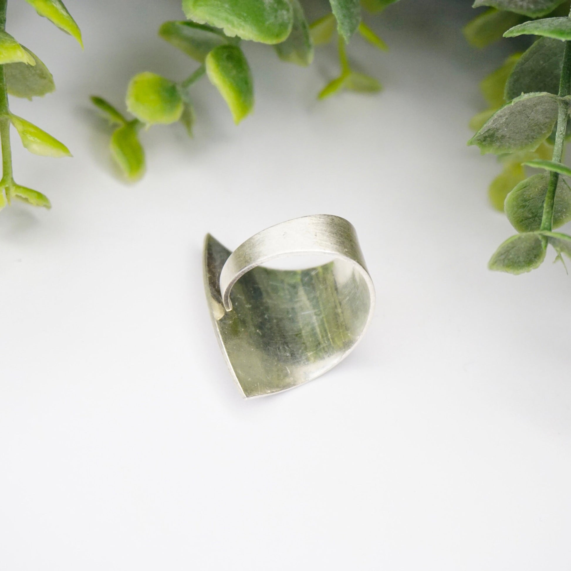 Vintage Kathy Lynn Mayeda sterling silver wrap ring featuring a modernist fan design, set against a background of green foliage.