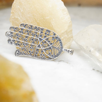 Vintage Sterling Silver Filigree Hamsa Hand Pendant on white crystal background, detailed silver hand pendant with intricate filigree design, protective talisman pendant made in Israel, 925 jewelry closeup