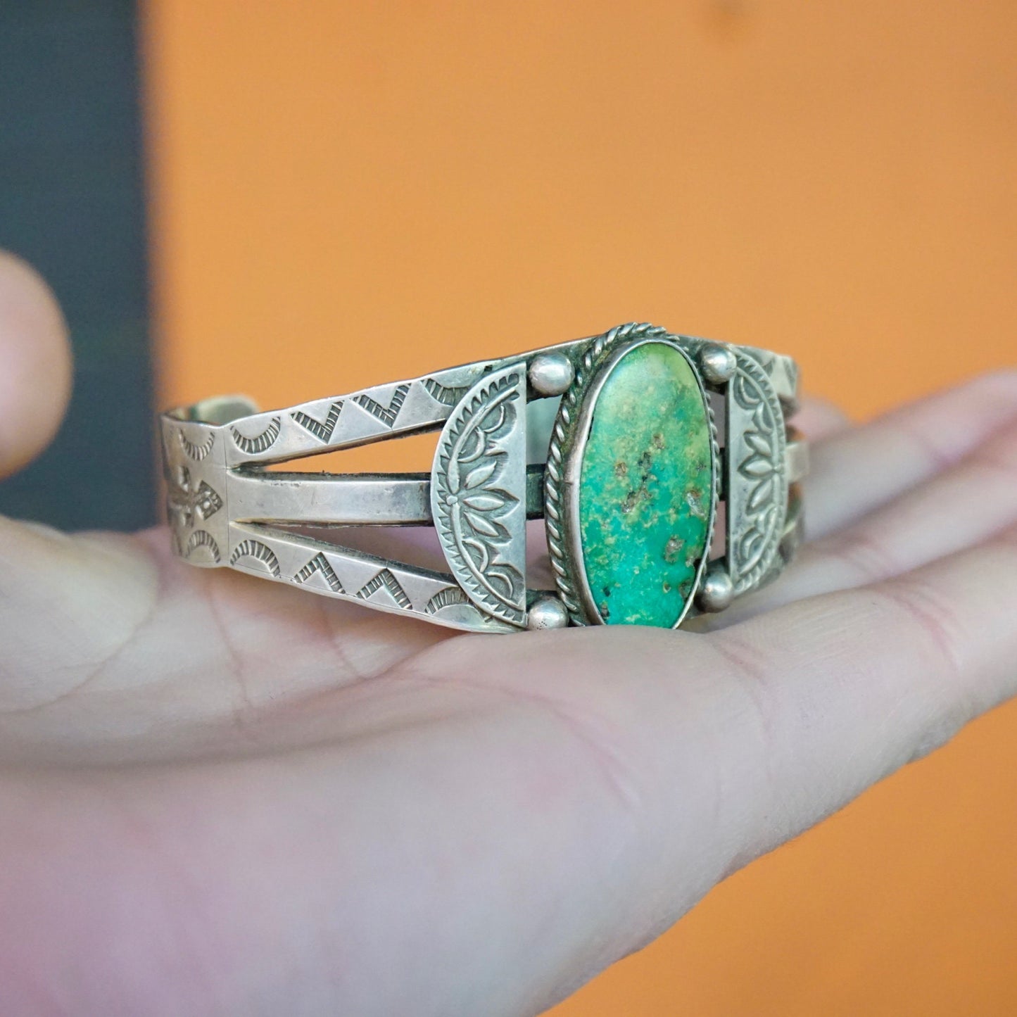 Vintage Native American coin silver cuff bracelet featuring intricate stamped designs and a natural turquoise stone, handcrafted old pawn jewelry.