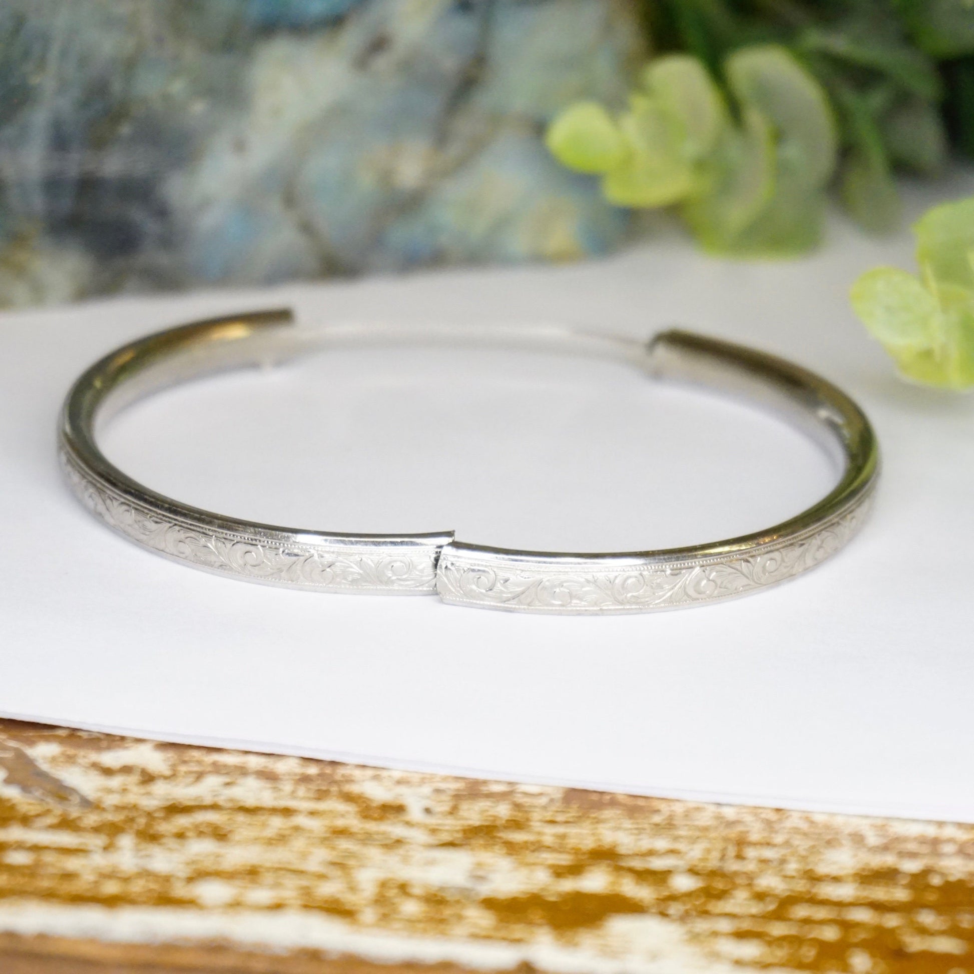 Vintage sterling silver bangle bracelet with intricate engravings and scroll clasp, handcrafted by Craftmere.