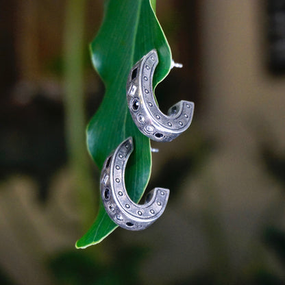 Vintage Patricia Lock silver plated earrings featuring multiple crescent-shaped hoops adorned with black and white crystals on a green leaf, showcasing a modernist design.