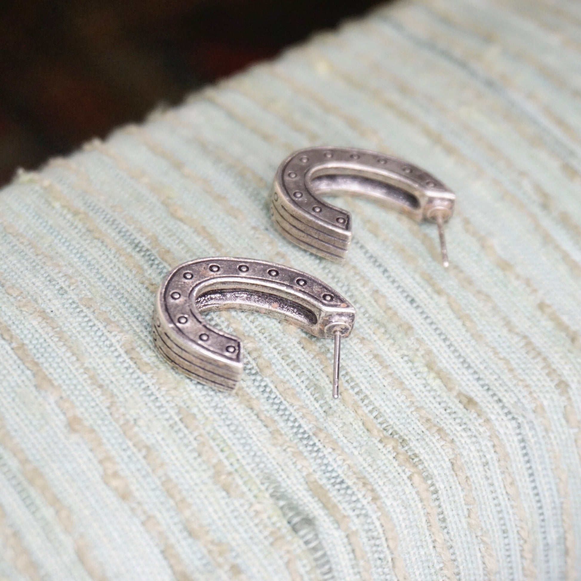 Vintage silver plated half moon stud earrings with black and white crystals on a woven textile background