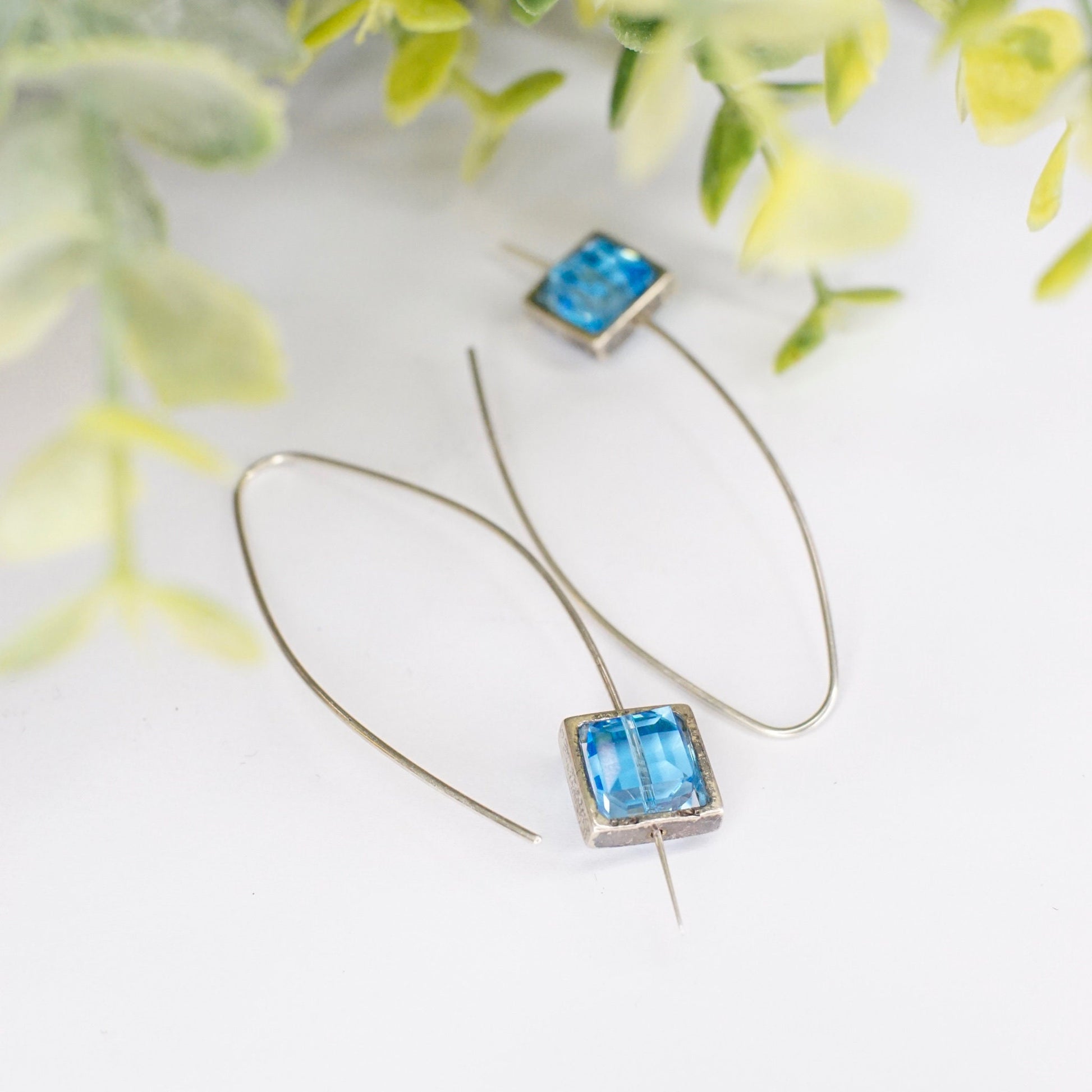 Blue glass and sterling silver minimalist hook earrings on floral background