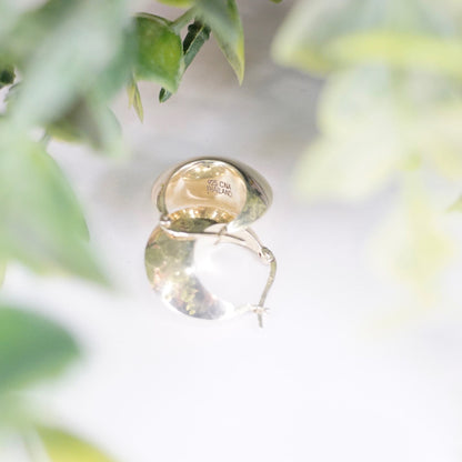 Vintage sterling silver half moon hoop earrings nestled in green foliage, showing the intricate details and markings on the minimalist 925 silver jewelry from Thailand.