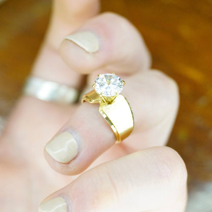 Vintage gold tone solitaire ring with round cut cubic zirconia on a hand