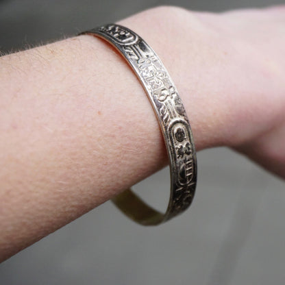 Vintage TAXCO Sterling Silver Hieroglyphic Bangle Bracelet with Egyptian motifs, worn on a wrist, showcasing intricate designs and 925 silver craftsmanship from Mexico.