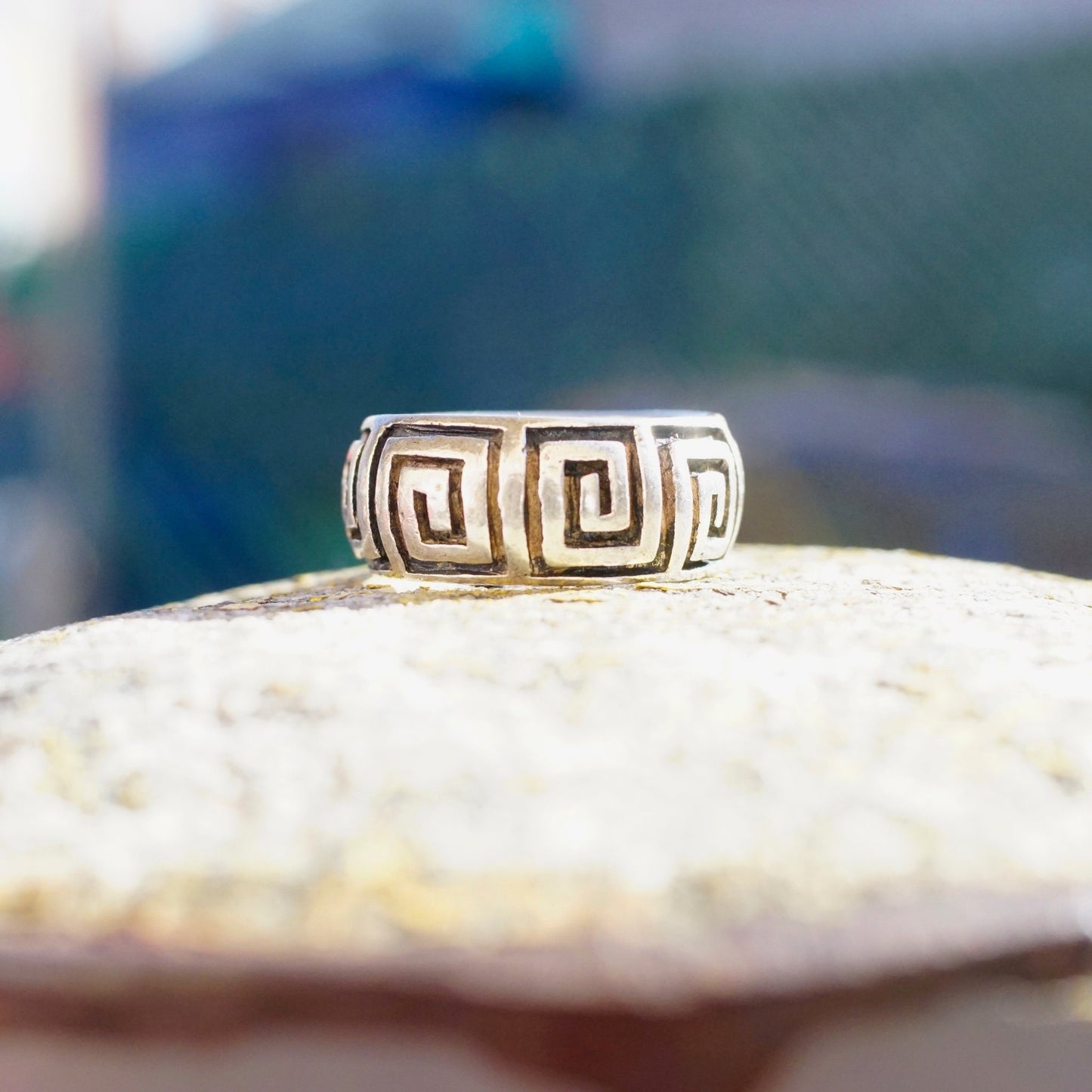 Vintage sterling silver square swirl Greek key band ring on textured stone surface