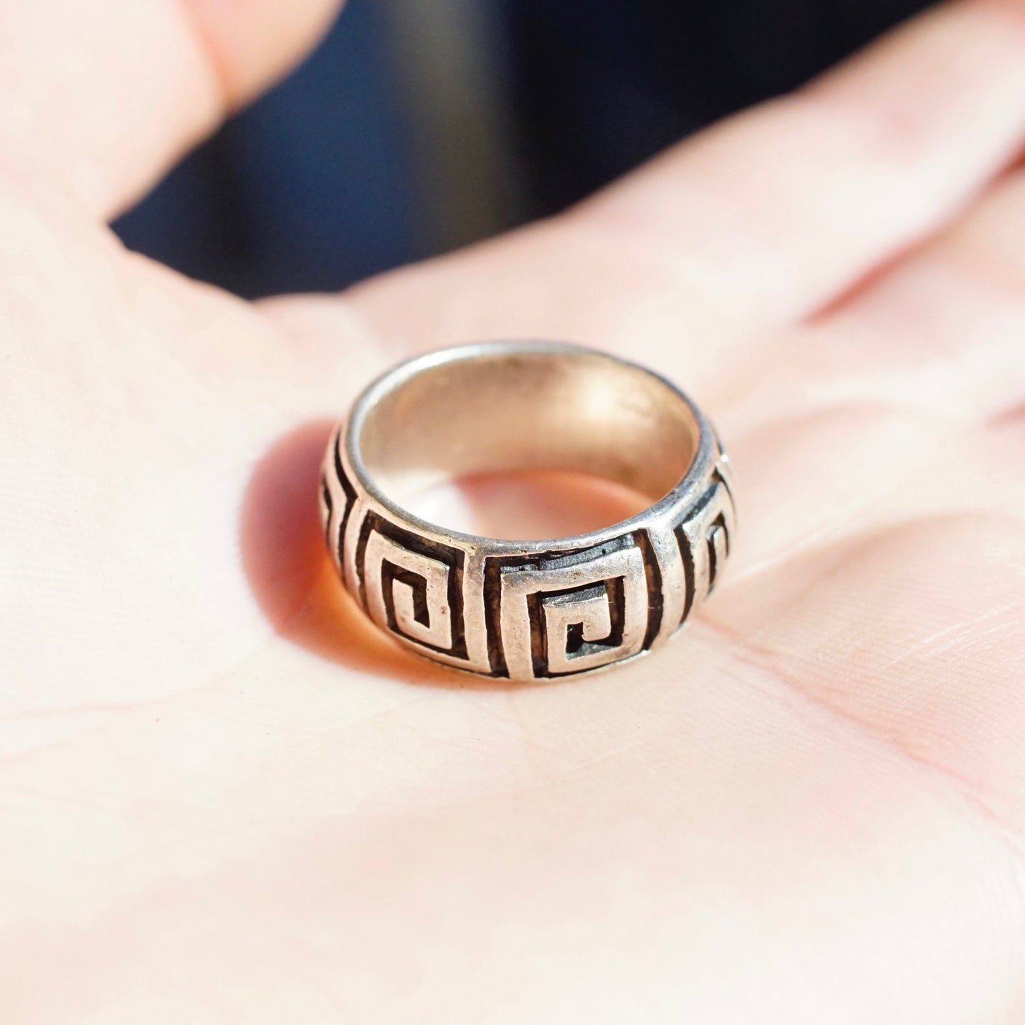 Vintage sterling silver square swirl Greek key band ring, size 9 3/4 US, held in palm of hand