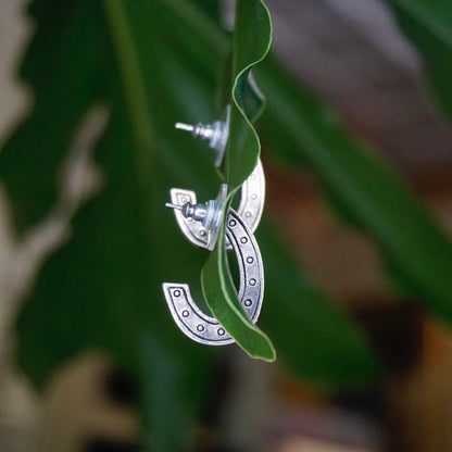 Vintage silver plated crescent moon stud earrings with black and white crystals hanging from green foliage