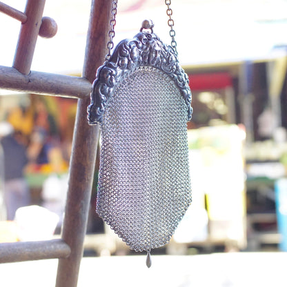 Antique Art Nouveau sterling silver chainmail mesh purse with embossed decorative frame, hanging from display rack, 925 silver vintage coin purse in excellent condition.