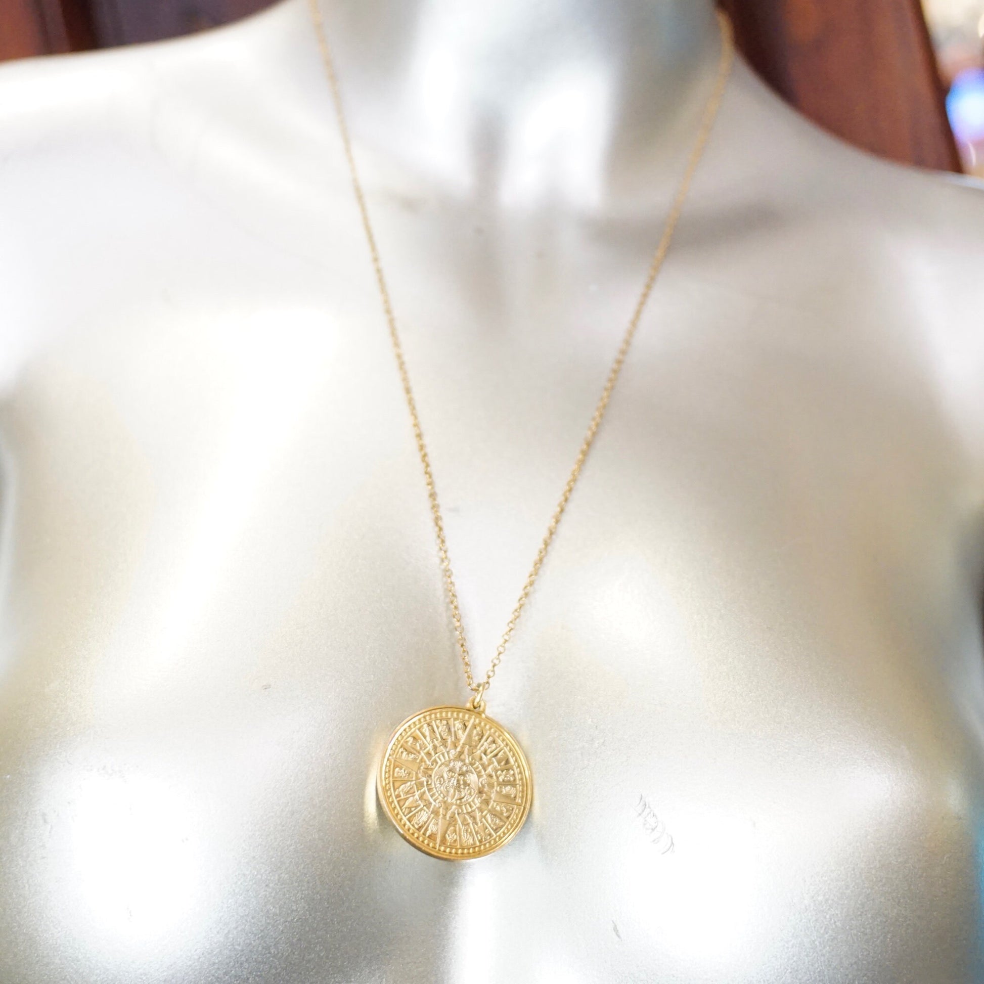 Vintage 24K gold-plated sterling silver Mayan sun calendar pendant necklace on mannequin, featuring detailed Aztec sun god medallion design, double-sided round pendant, and 24-inch cable chain.