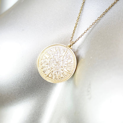 Vintage 24KT gold electroplated sterling silver Mayan sun calendar pendant necklace with double-sided Aztec sun god medallion design on a 24 inch cable chain, shown on a white silk fabric background.