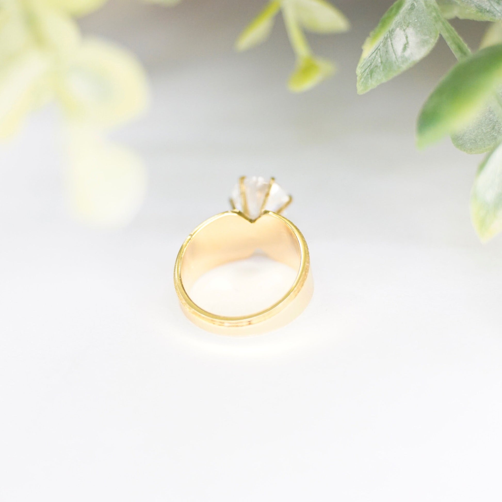 Vintage gold tone solitaire ring with round cut cubic zirconia in 6-prong setting on delicate leaves background, size 5 US