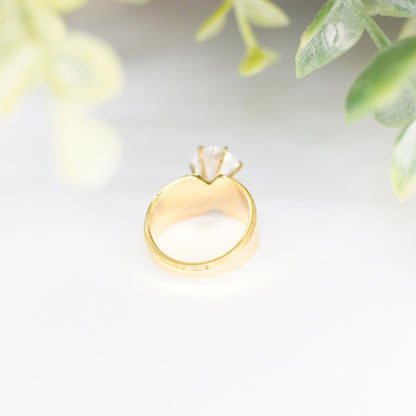 Vintage gold tone solitaire ring with round cut cubic zirconia in 6-prong setting on delicate leaves background, size 5 US