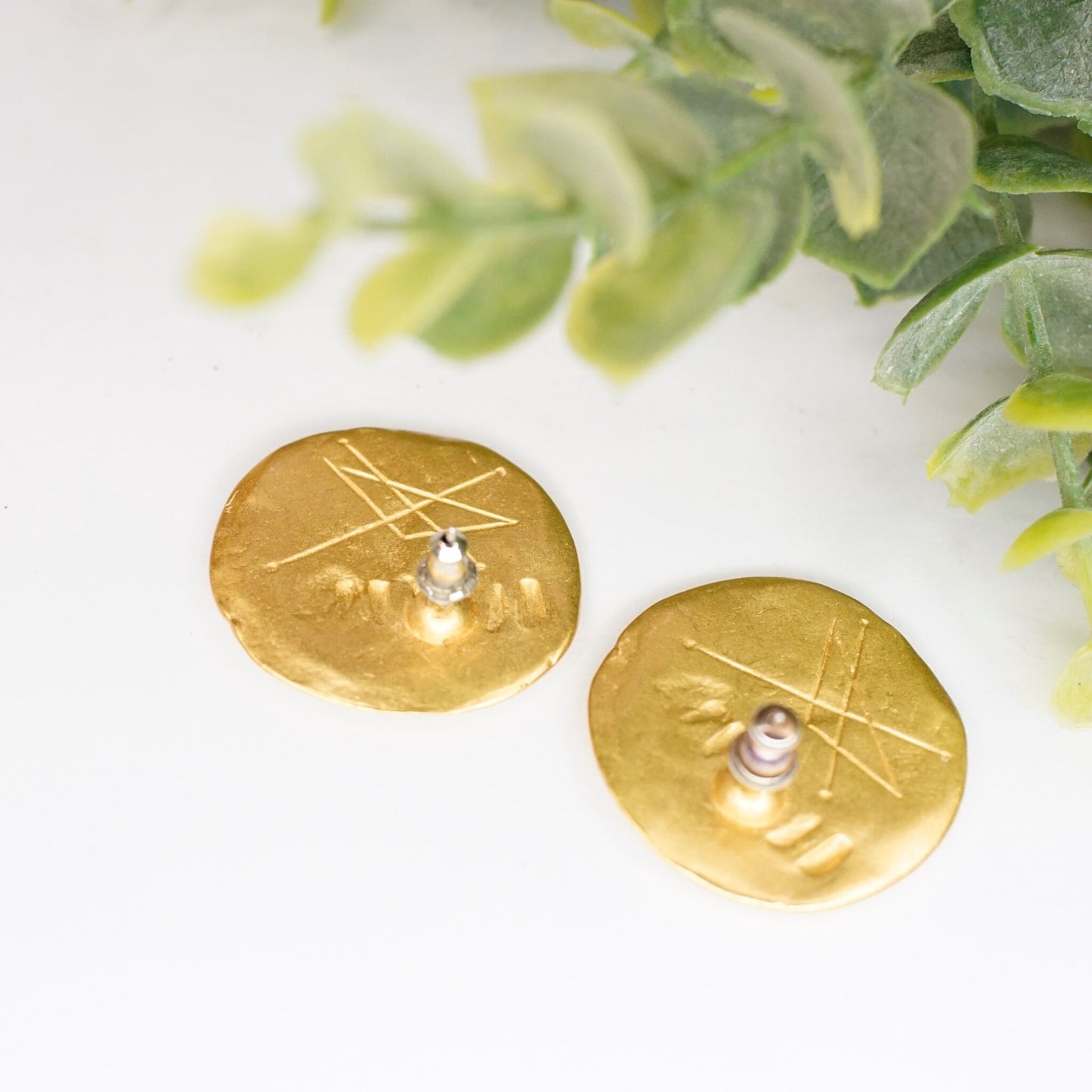 Vintage gold tone abstract hammered disc stud earrings with pearl accents and greenery in soft focus background