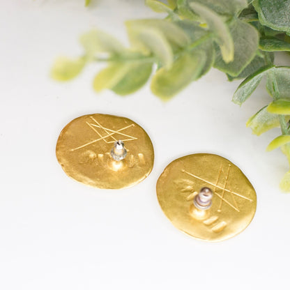 Vintage gold tone abstract hammered disc stud earrings with pearl accents and greenery in soft focus background