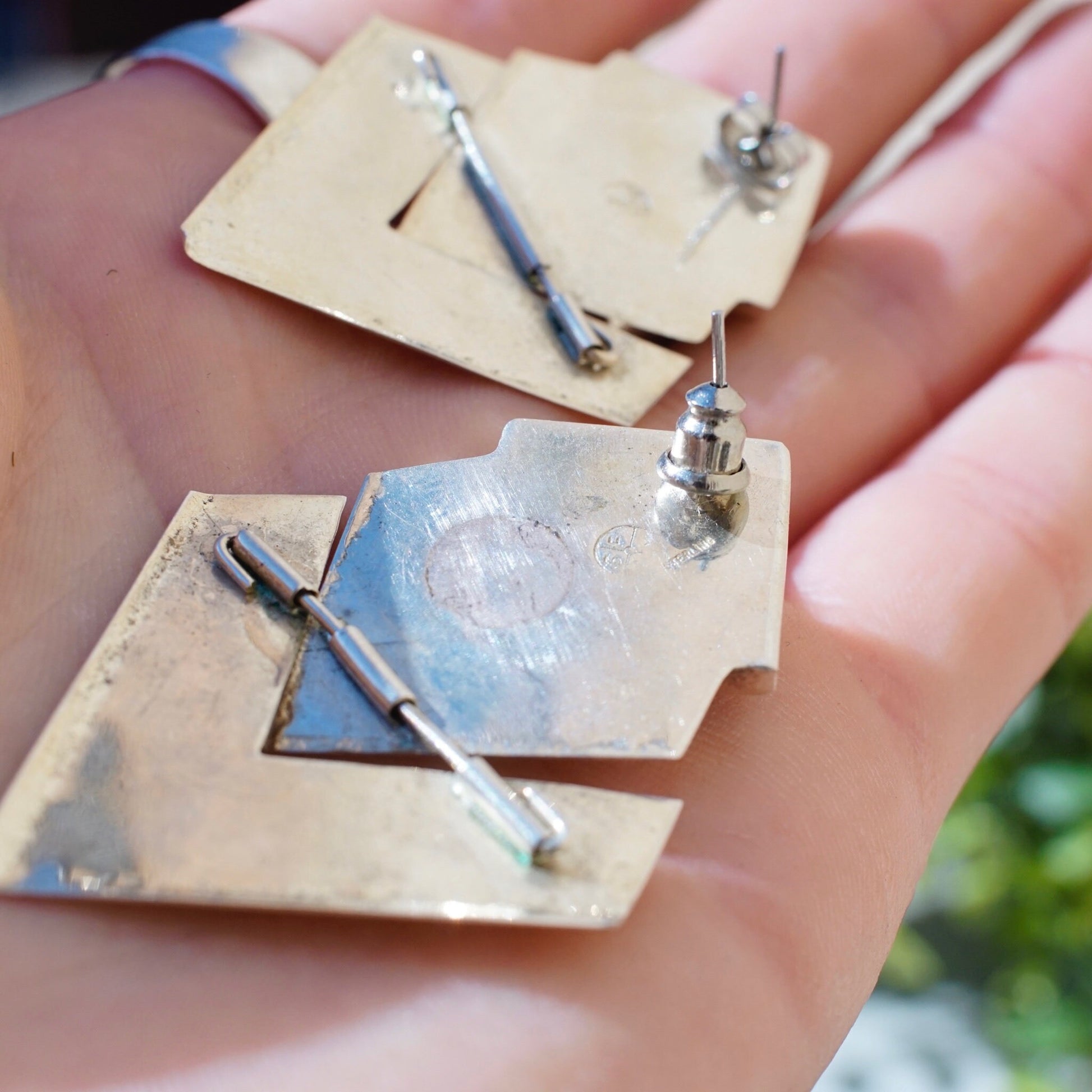 Vintage sterling silver modernist checker earrings with inlaid glass or stone, featuring unique hinged stud and dangle post design, shown in hand to display size and detail of the 925 silver jewelry.